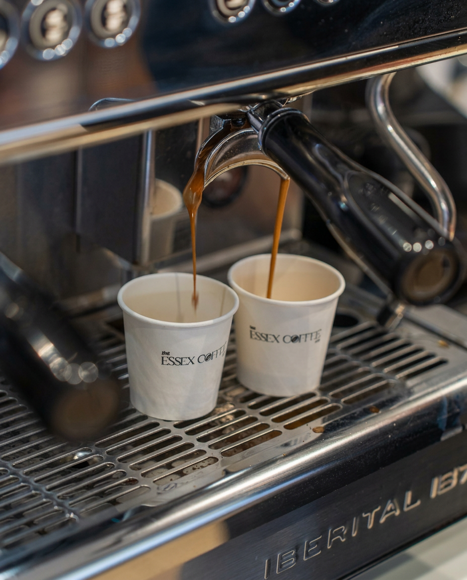 Espresso extracting into two branded Essex Coffee Co. takeaway cups.